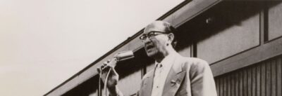 Dokter Que spreekt het publiek toe tijdens de eerste vlaggetjesdag, in 1959